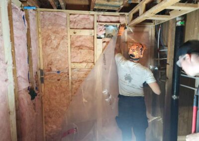 Two men install vapour barrier on newly insulated basement space