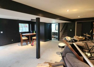Basement with black walls and white ceiling. Furniture has been stacked to the side
