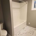 New bathroom with white tub, tiles and grey walls