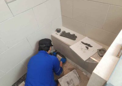 Man installs black hexagonal tiles on floor of shower