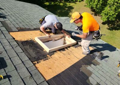 Two men stand on roof installing frame for skylight